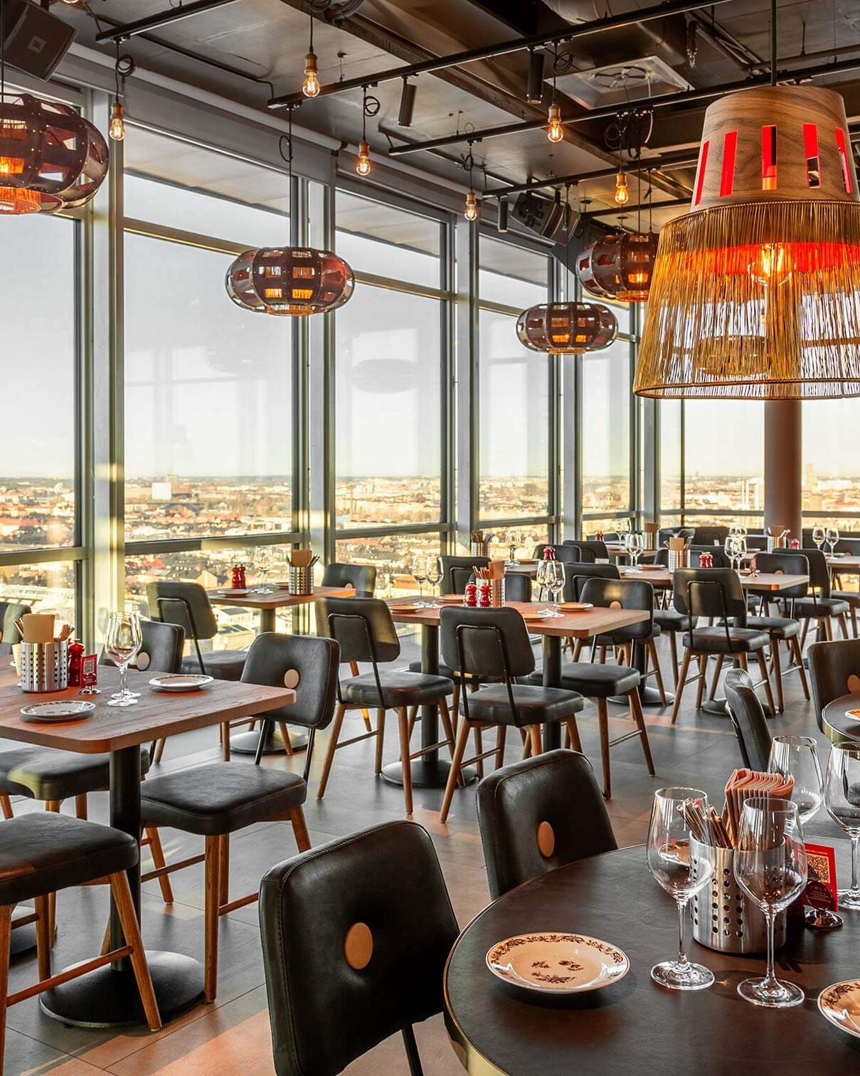 Novum Kitchens matsal med dukade bord och utsikt över staden i kvällsljus